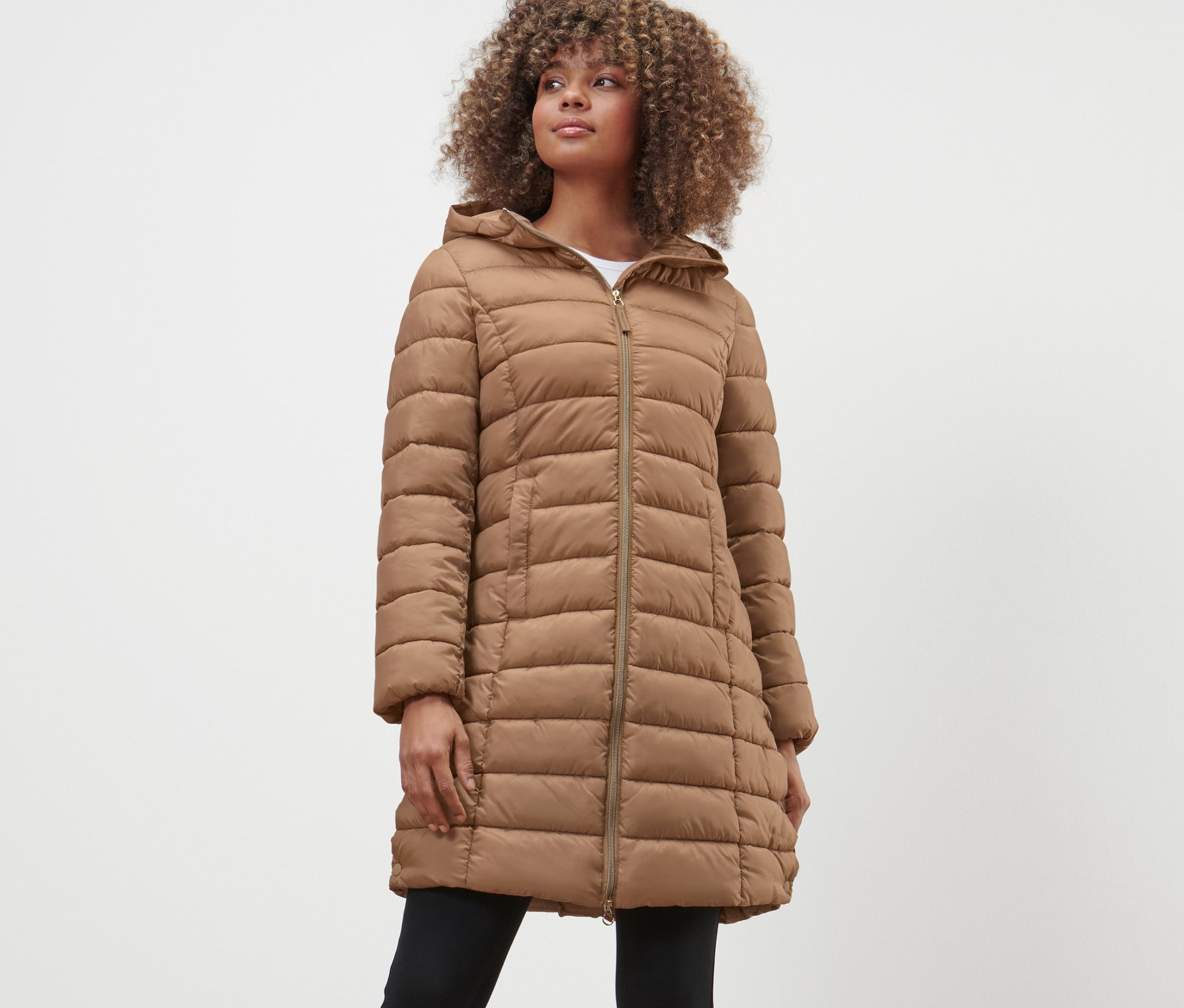 Žena má na sobě prošívaný kabát s kapucí.