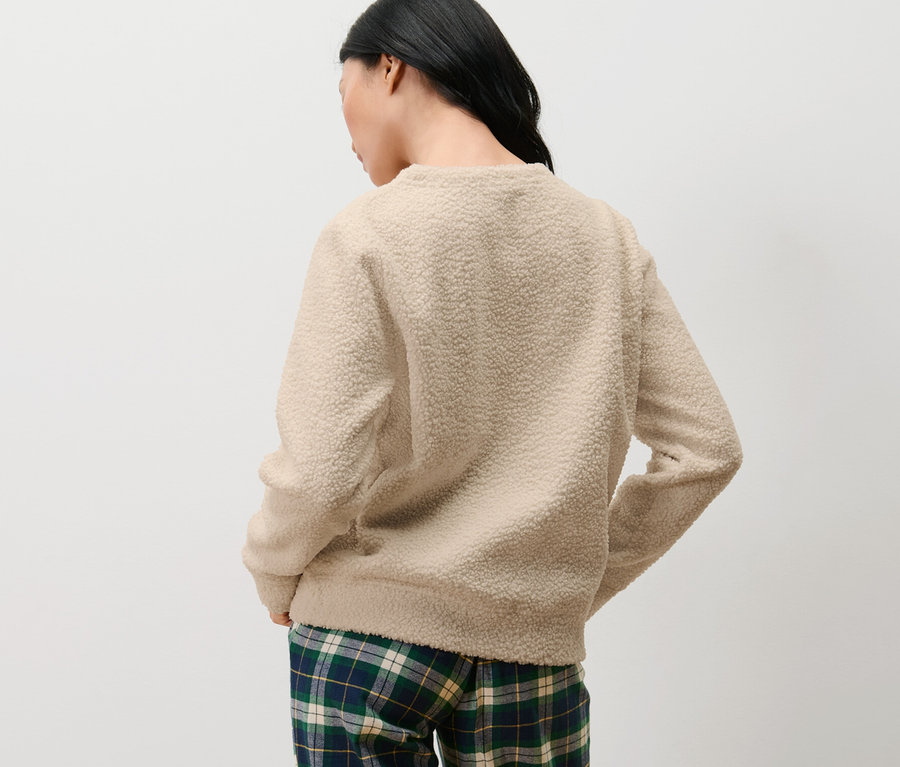 Žena stojí zády a má na sobě měkoučký svetr a kostkované kalhoty.