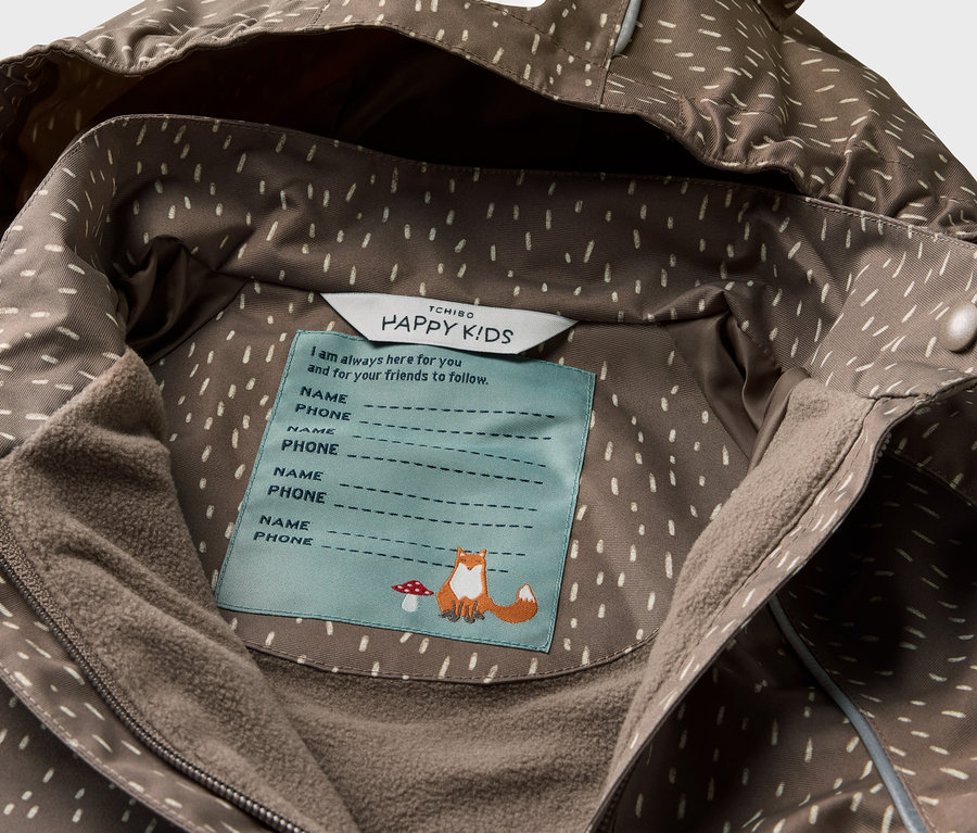 Detail dětské termobundy do deště s kapucí s motivem medvěda a vnitřním štítkem.