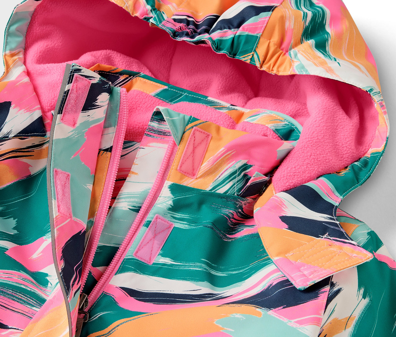 Detail bundy s kapucí s barevným vzorem a růžovou podšívkou.