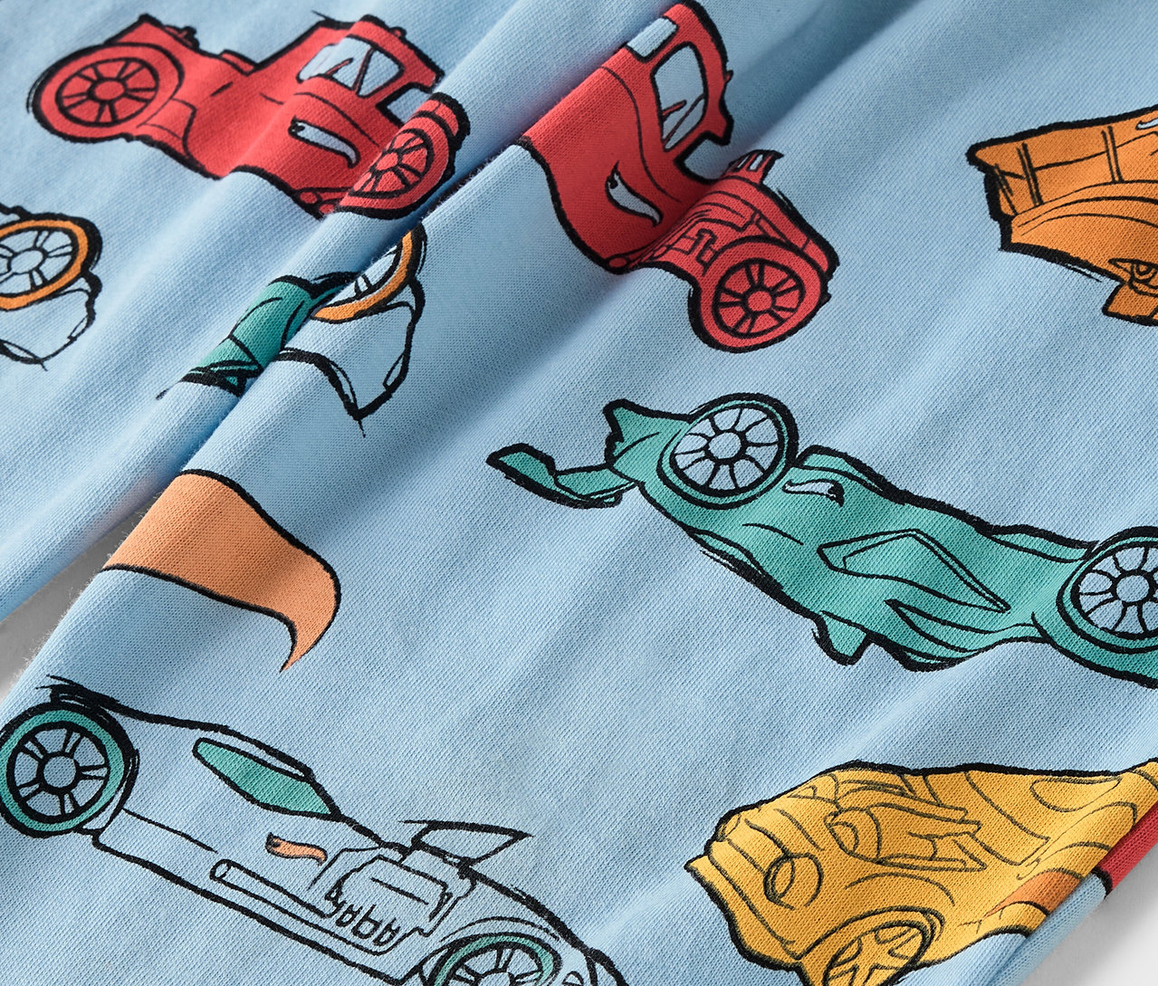 Světle modrá látka s potiskem barevných aut.