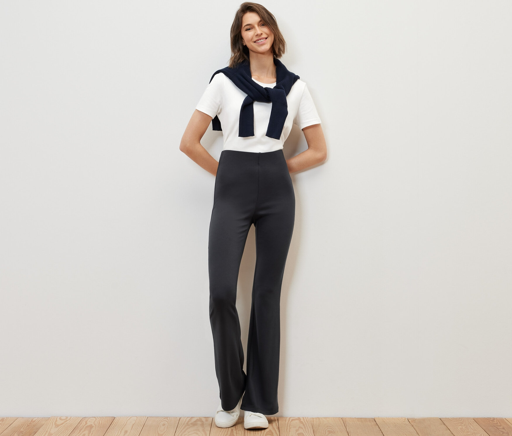 Žena stojí a pózuje v rozšířených legínách.