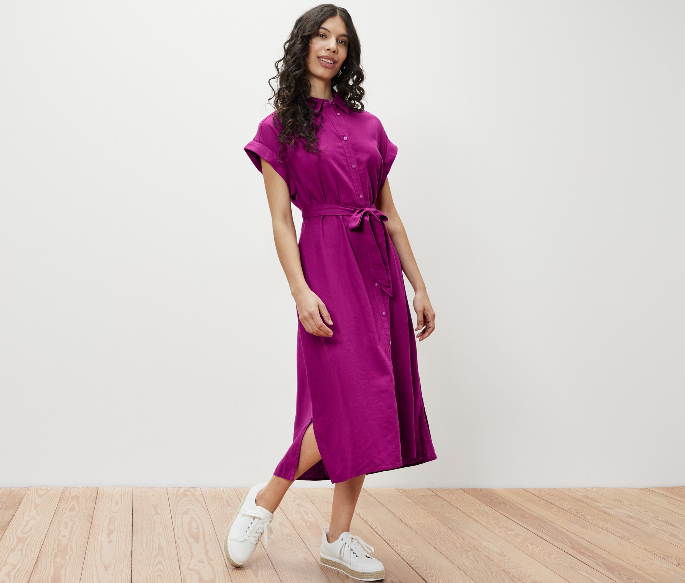 Žena pózuje v lněných šatech.