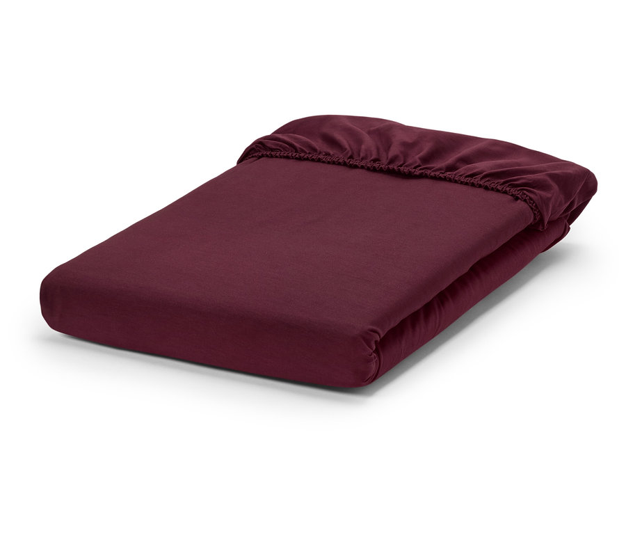 Vínové prostěradlo s gumou složené na bílém pozadí.