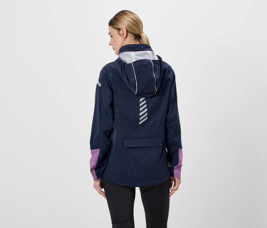 Zezadu je vidět žena v tmavě modré bundě s kapucí, černých kalhotách a fialovými rukávy.