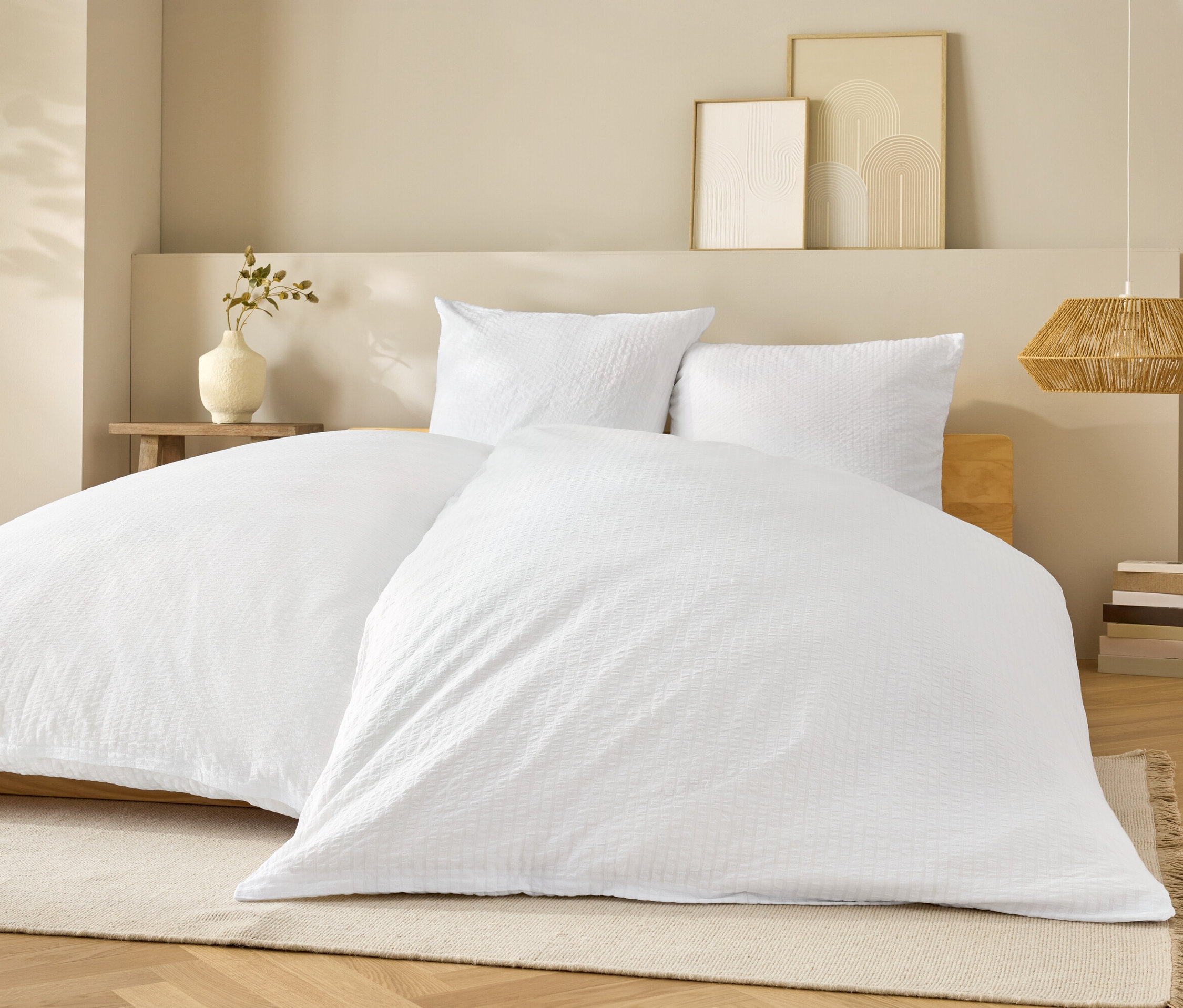 Bílé ložní prádlo na posteli s bílými polštáři.