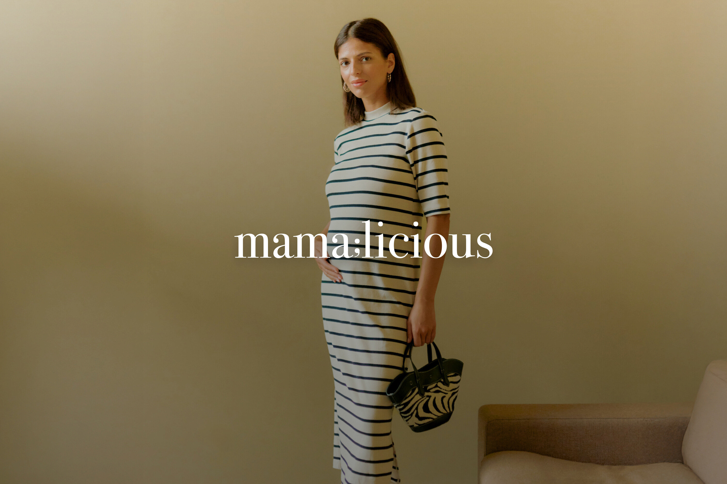 Těhotná žena má na sobě pruhované šaty a drží kabelku se zebrou.