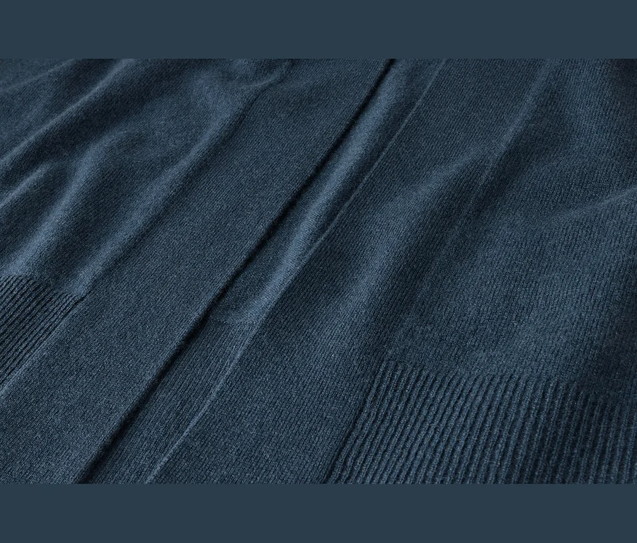 Detail tmavě modré pletené látky s měkkou texturou, záhyby a žebrovanými okraji.