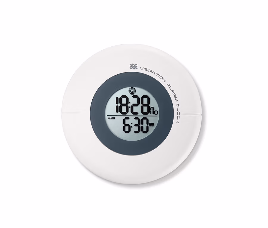 Detailní záběr na Vibrační budík řízený rádiovým signálem, který ukazuje čas 18:28 a nastavený budík na 6:30.