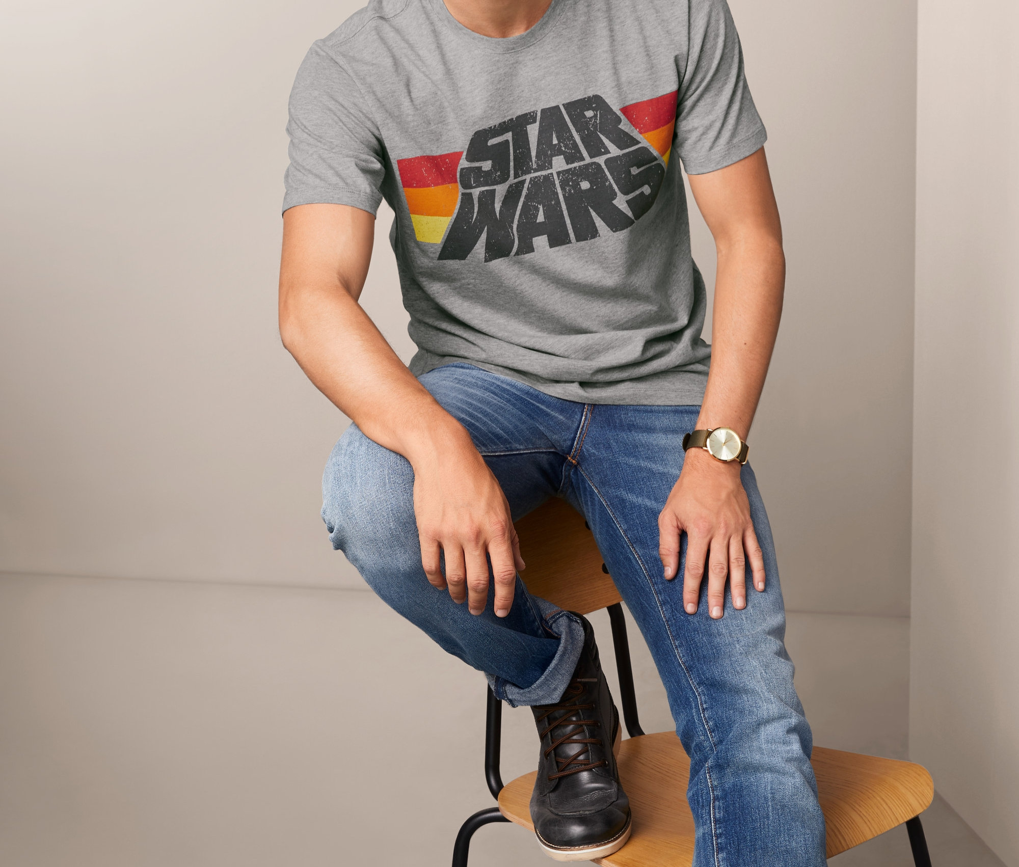 Muž sedí na židli a má na sobě šedé tričko s nápisem Star Wars.