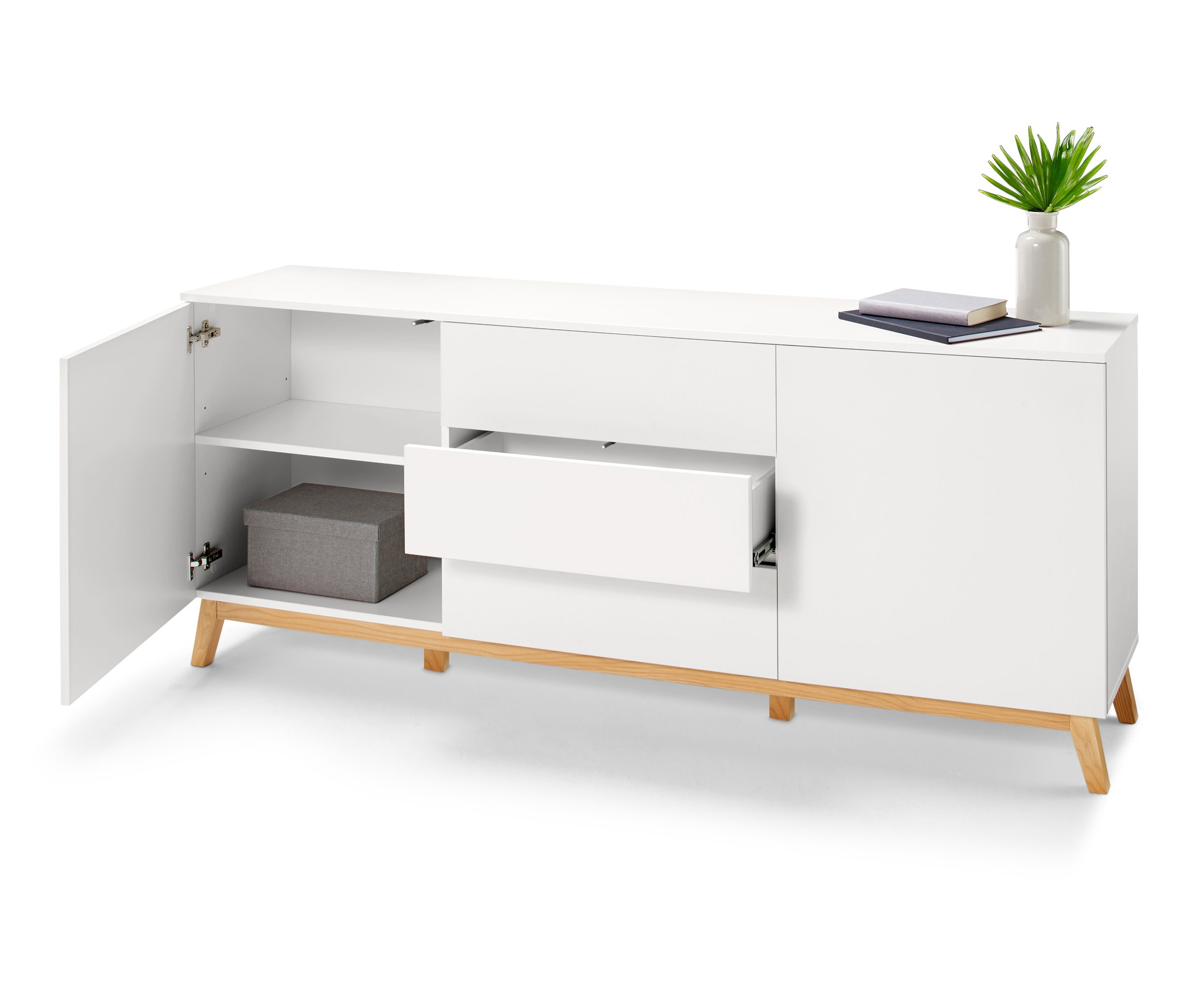 Bílá komoda s otevřenými dvířky a zásuvkou, na které leží knihy a váza.