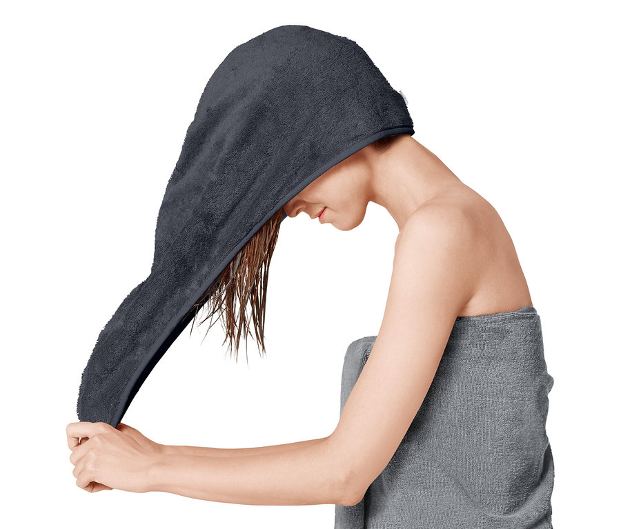 Žena si dává na mokré vlasy ručníkový turban.