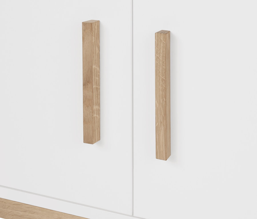 Detail bílé šatní skříně Eklund s dřevěnými úchyty.