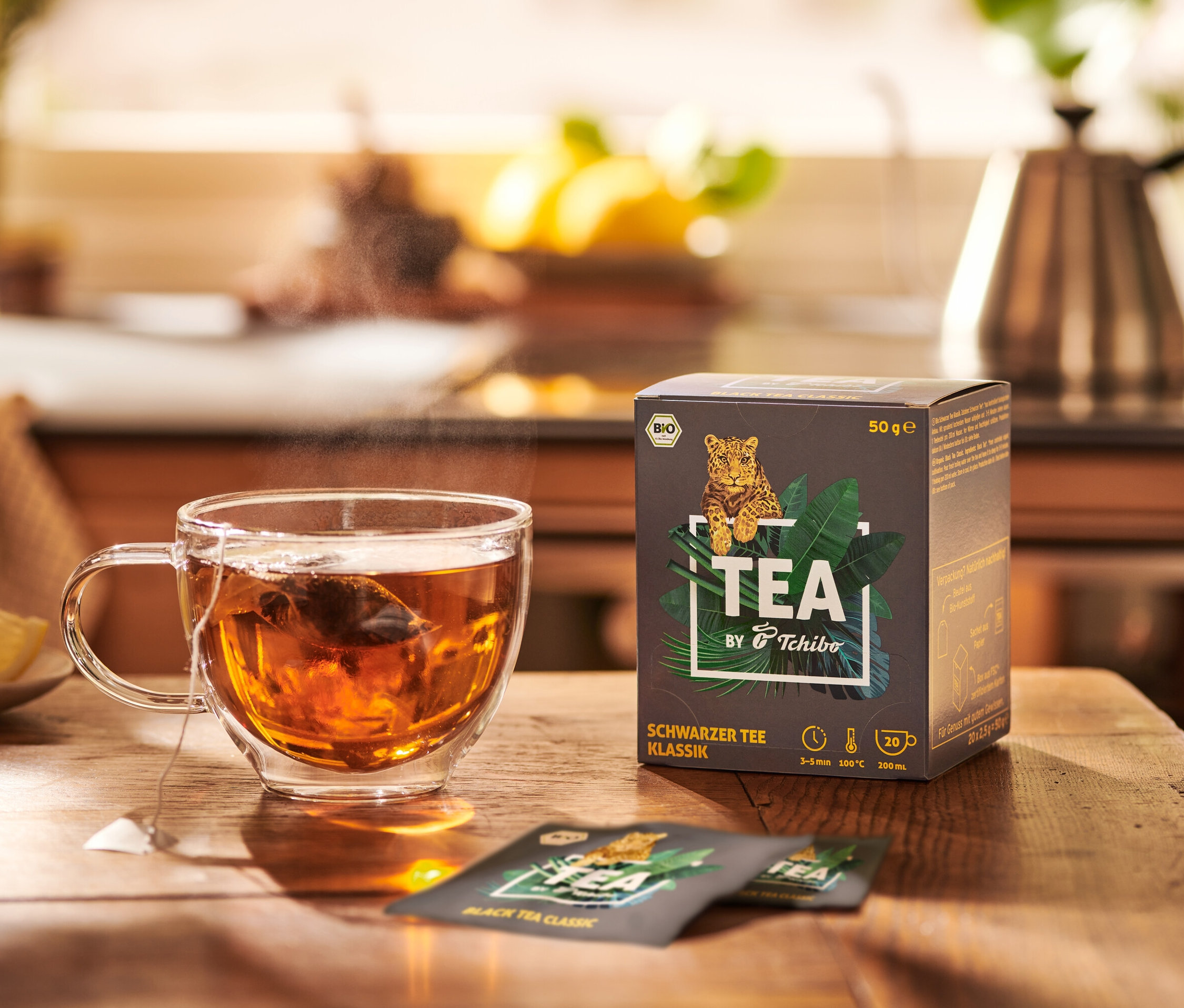 Šálek čaje vedle balení BIO TEA by Tchibo Klassik.