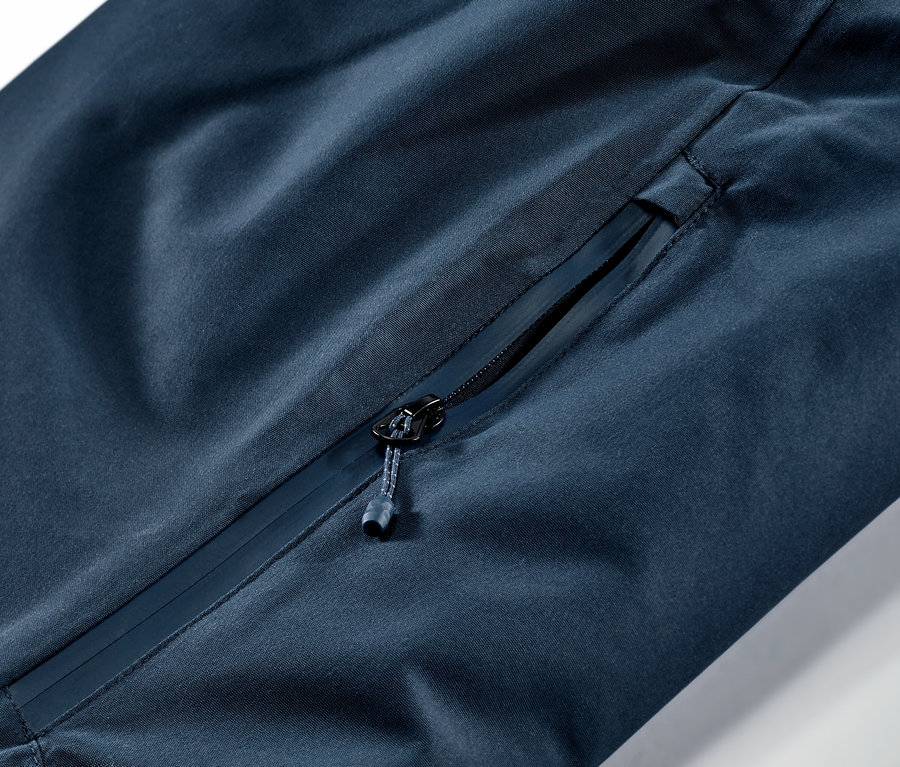 Detail námořnicky modrých lyžařských a snowboardových kalhot s kapsou na zip.