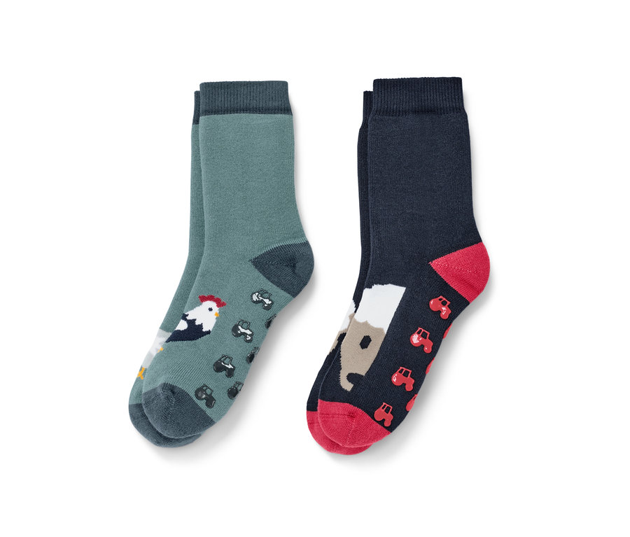 Dvoje dětské protiskluzové ponožky s motivem farmy. Jedny zelené s kohoutem a traktory, druhé tmavě modré s koněm a traktory.