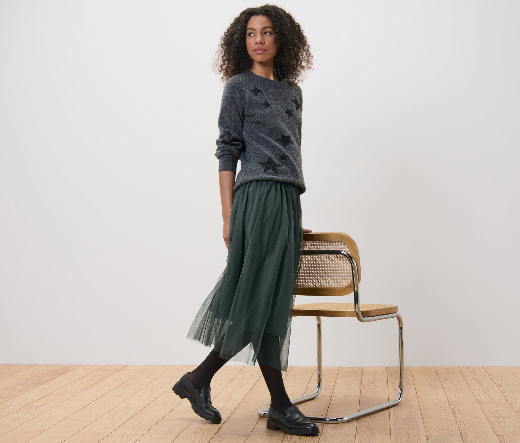 Žena v šedém svetru s hvězdami a tylové sukni.