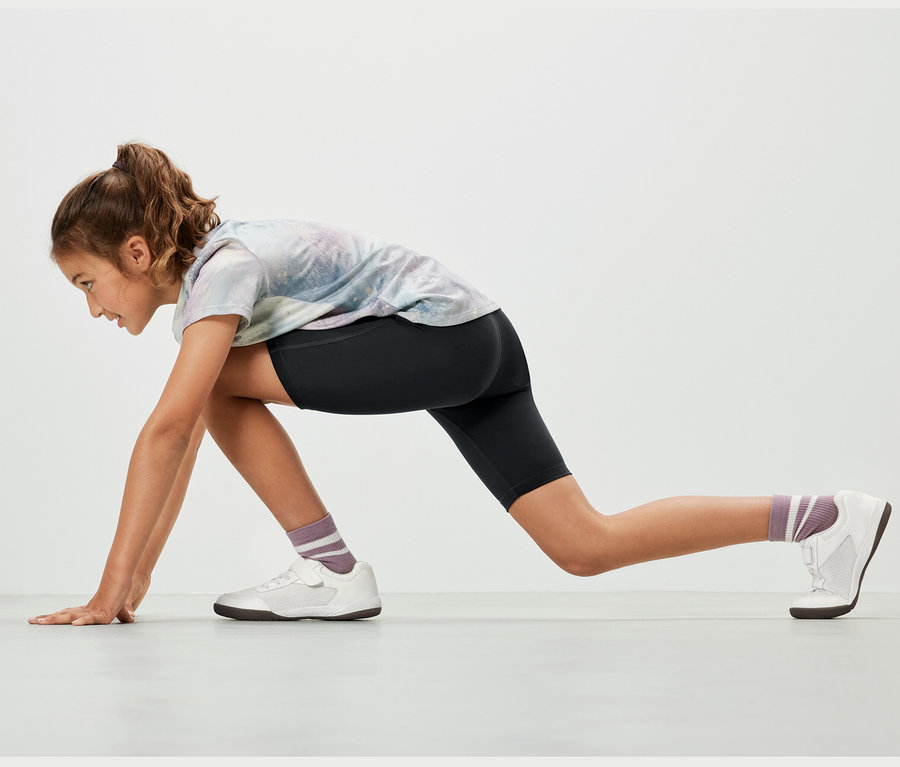 Dívka ve sportovní pozici má na sobě černé dětské sportovní šortky, 2 ks.