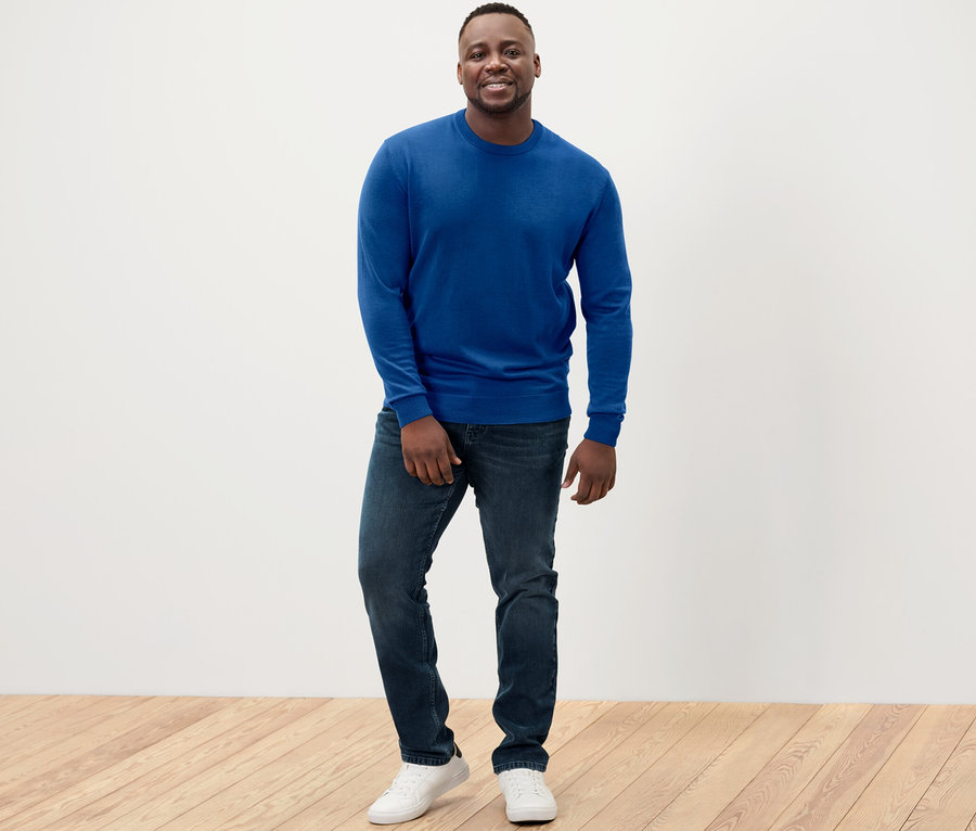 Muž stojí a má na sobě modrý svetr z vlny merino.