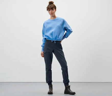 Žena pózuje v modré mikině a námořnicky modrých softshellových kalhotách joggpant.