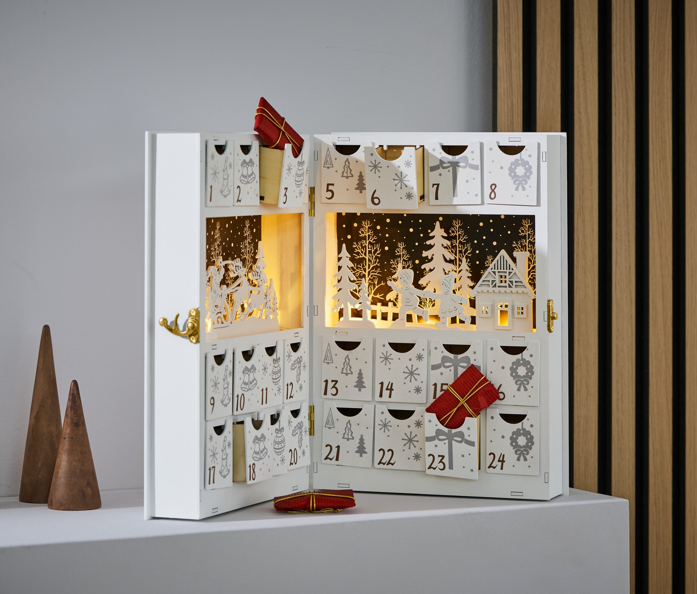 Otevřený adventní kalendář s LED světly a malými dárky v některých přihrádkách.