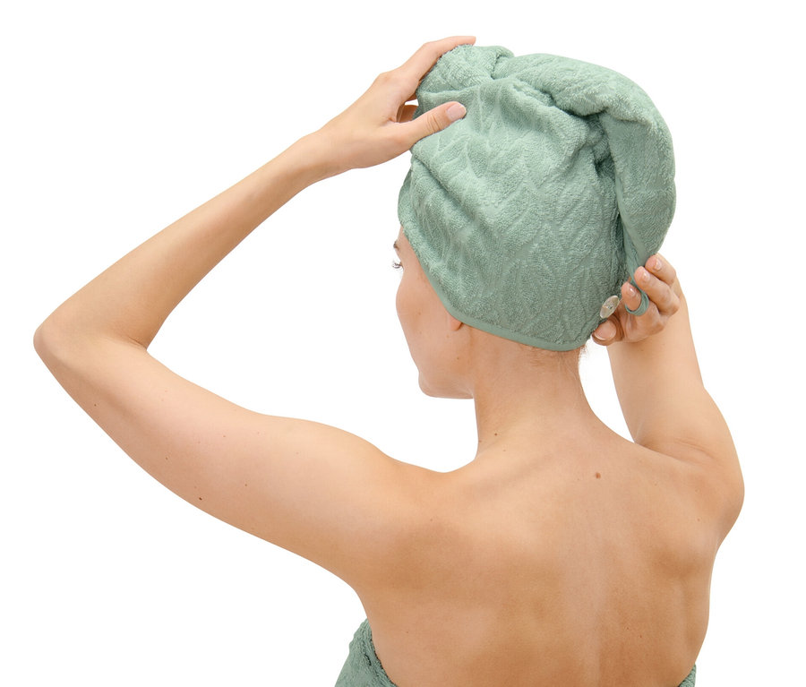 Žena si upravuje ručníkový turban na hlavě.