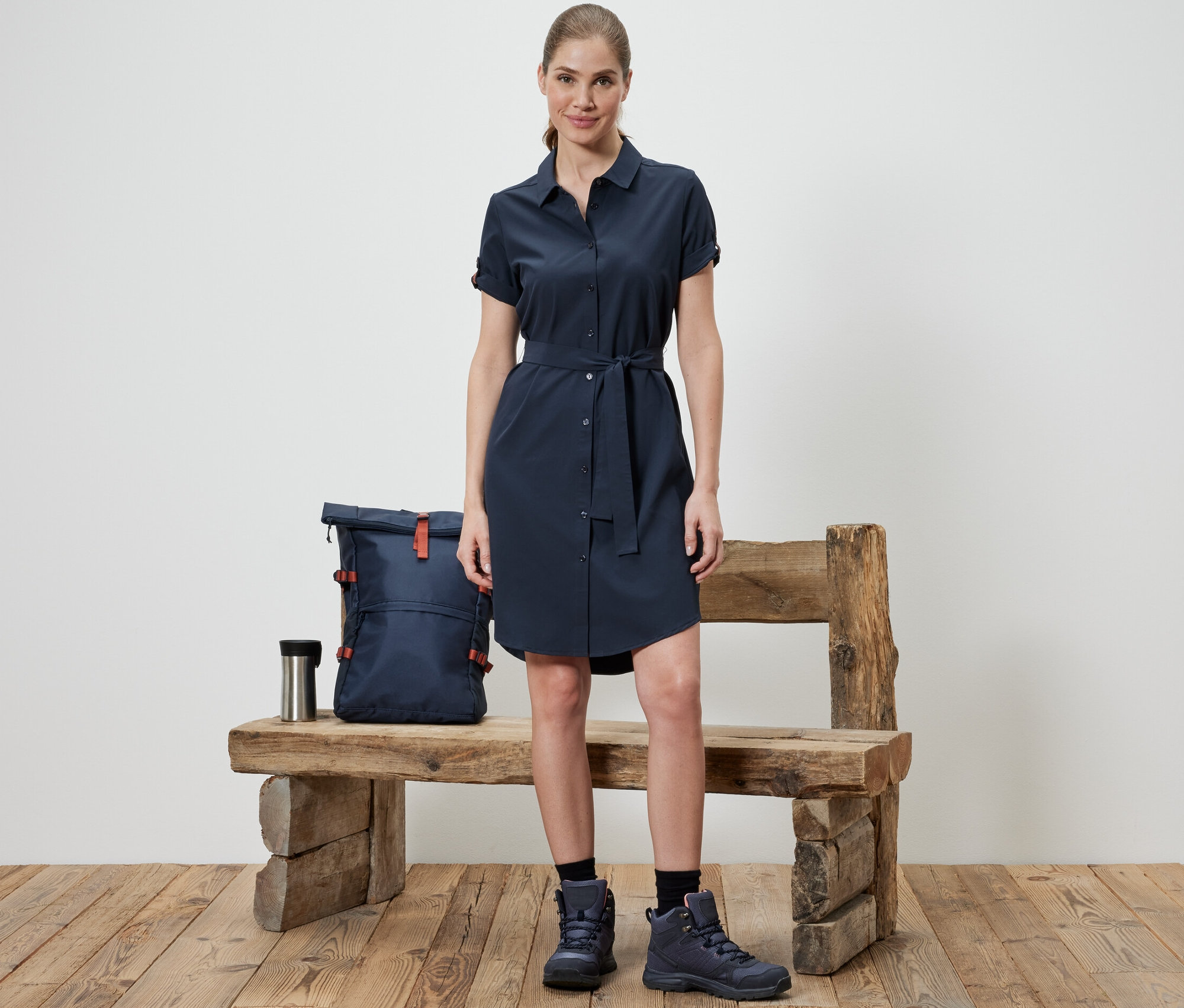Žena stojí před lavicí a má na sobě funkční šaty.