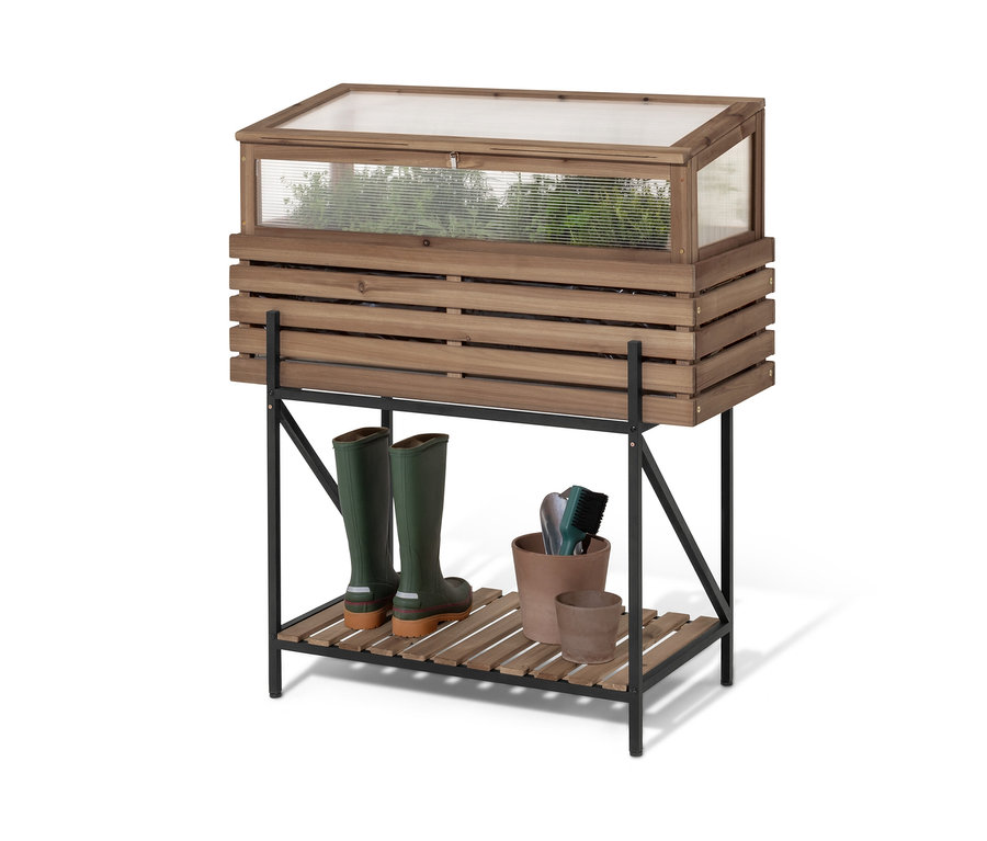 Vyvýšený truhlík se skleníkovým nástavcem »Elin« stojí na černé polici. Na polici jsou zelené holínky a květináče.