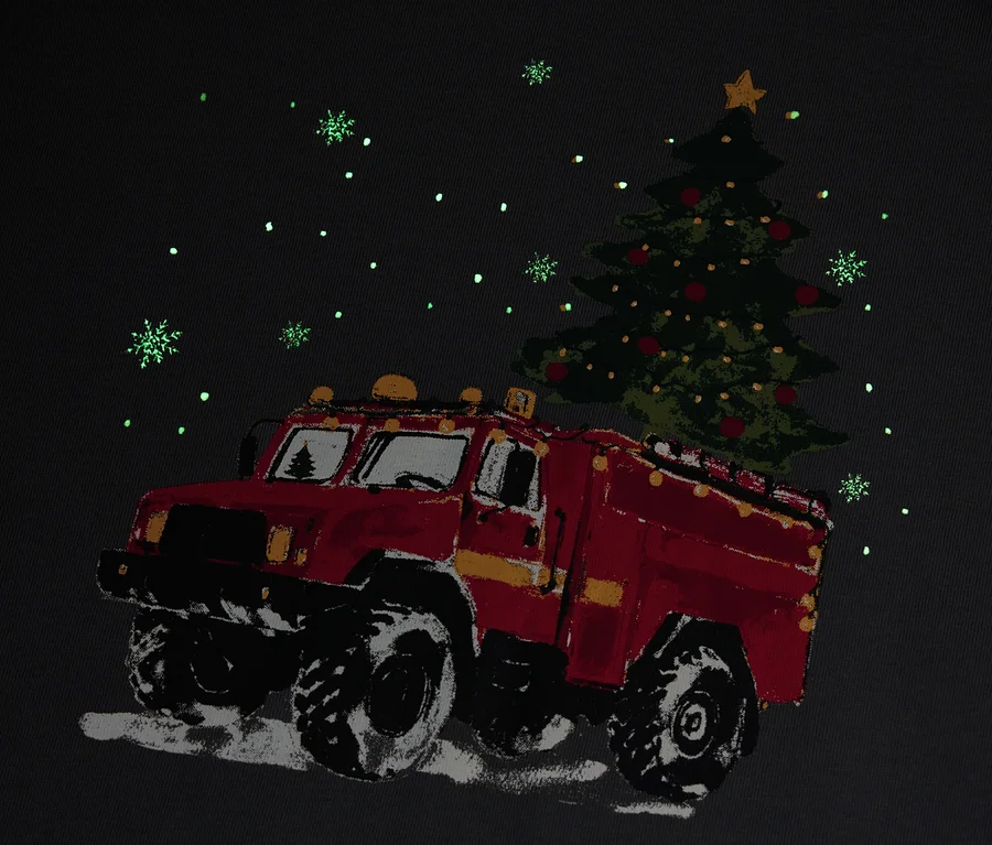Červené hasičské auto převáží vánoční stromek za sněžení.
