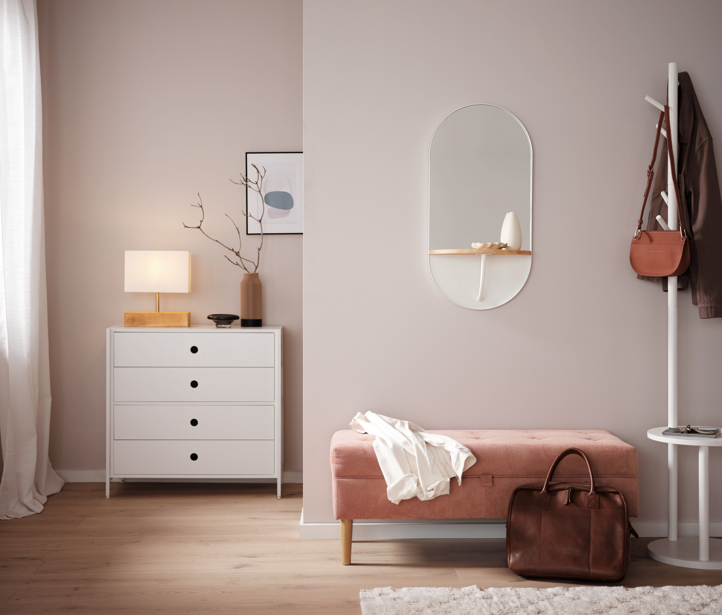Ložnice s bílou komodou, zrcadlem a růžovou lavicí.