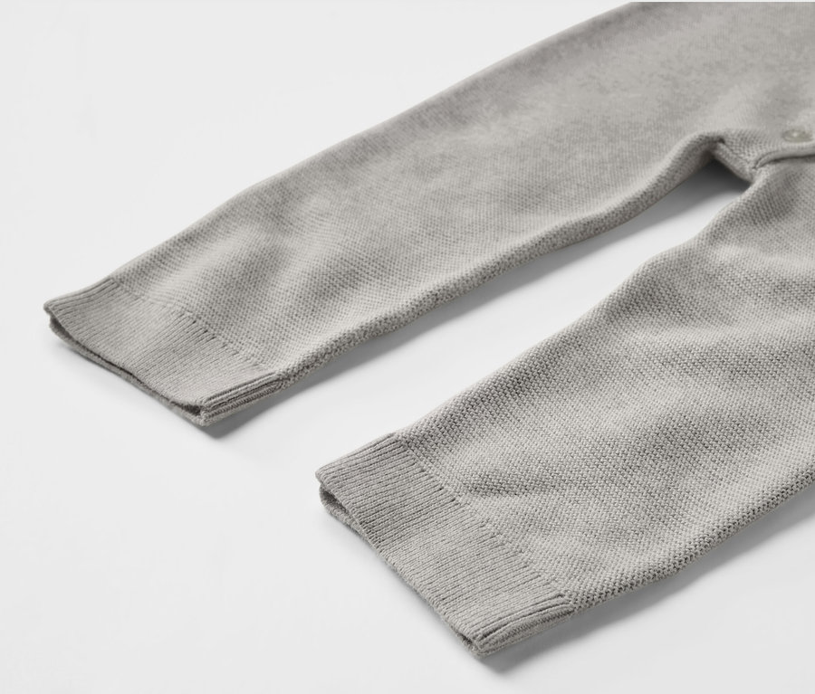 Detail pleteného overalu pro miminka šedé barvy.