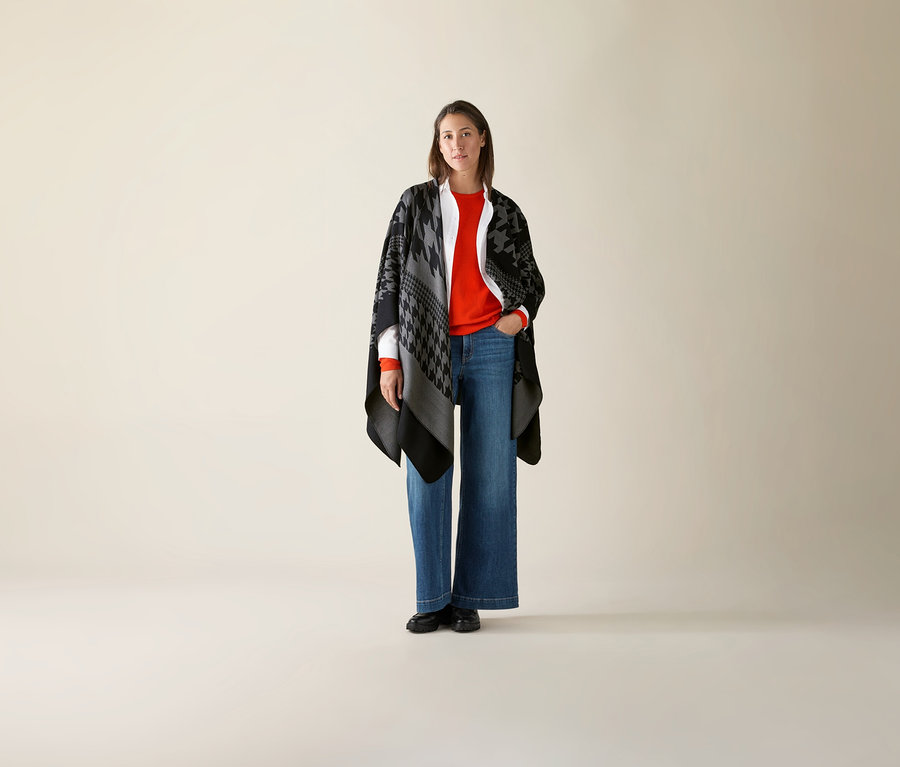 Žena stojící a má na sobě oranžový svetr z jemného úpletu merino.