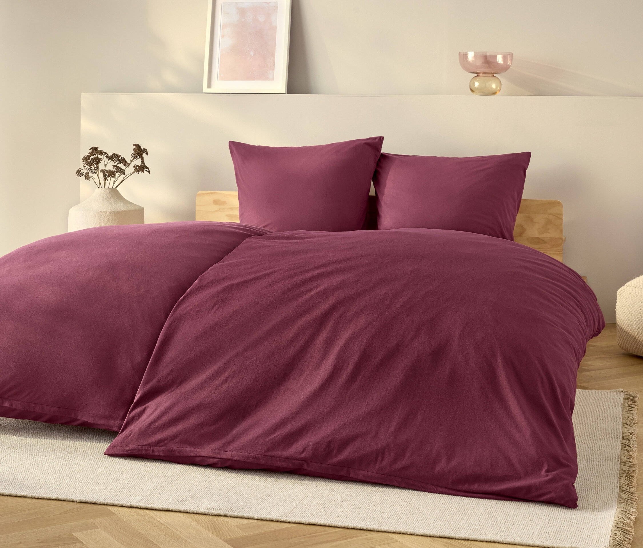 Nachová ložní souprava na posteli s bílým kobercem.