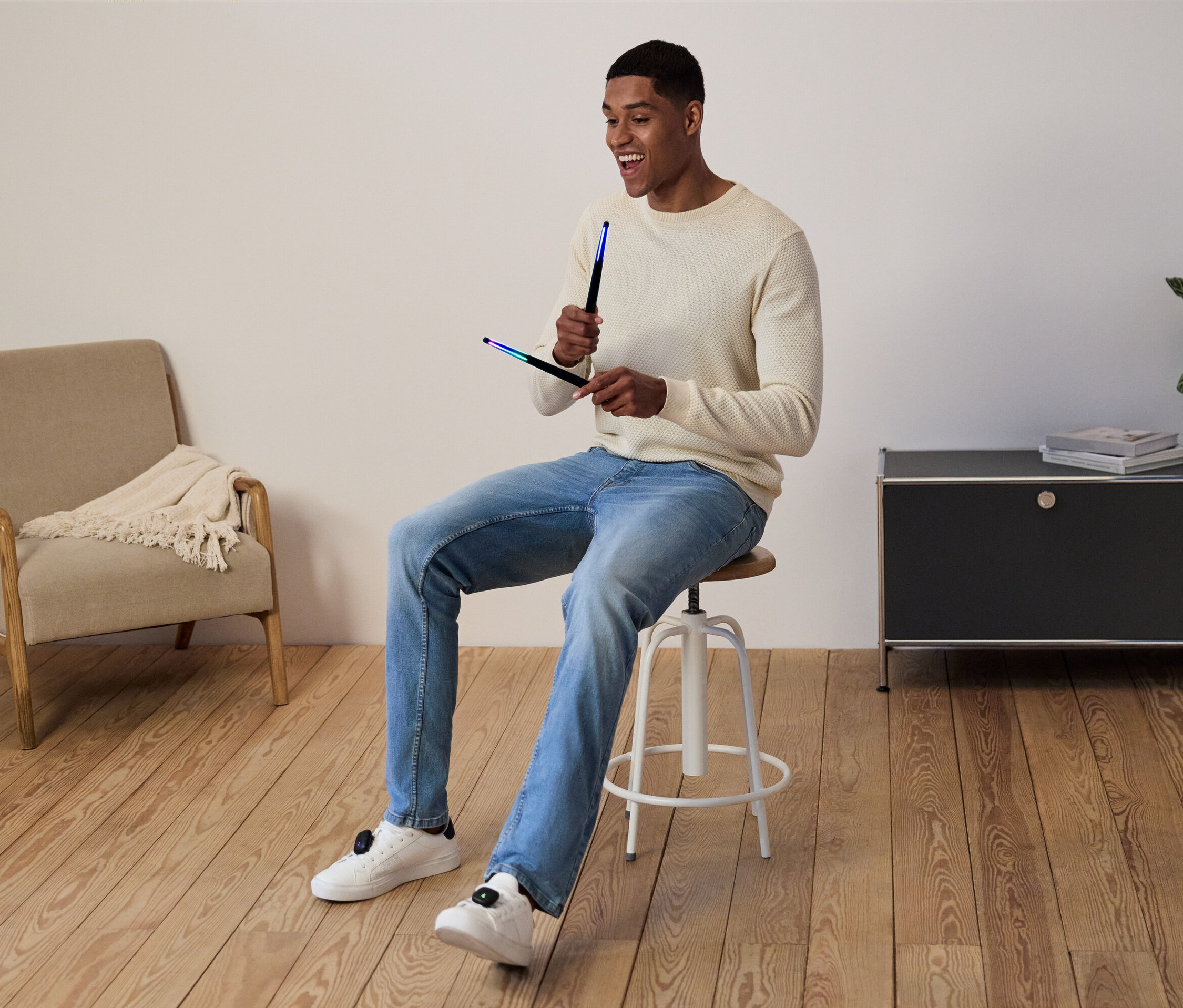 Muž sedí na stoličce a v rukou drží světelné tyče.