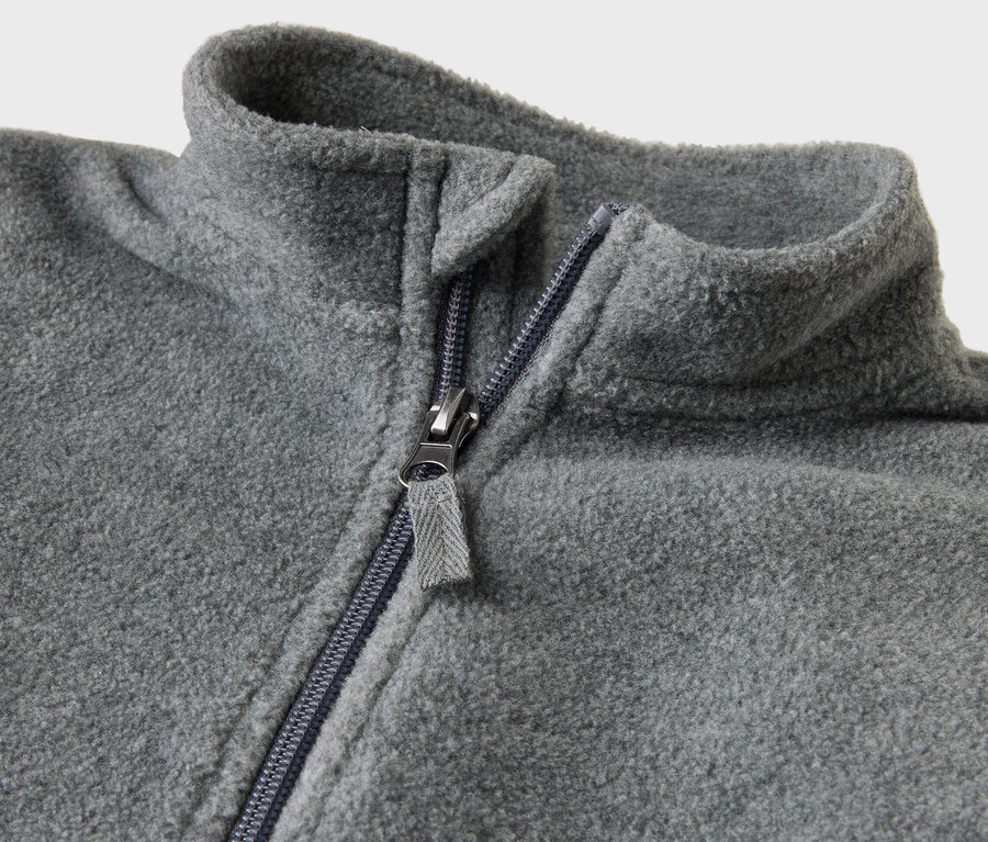 Detail šedého fleecového overalu pro miminka s rozepnutým zipem.