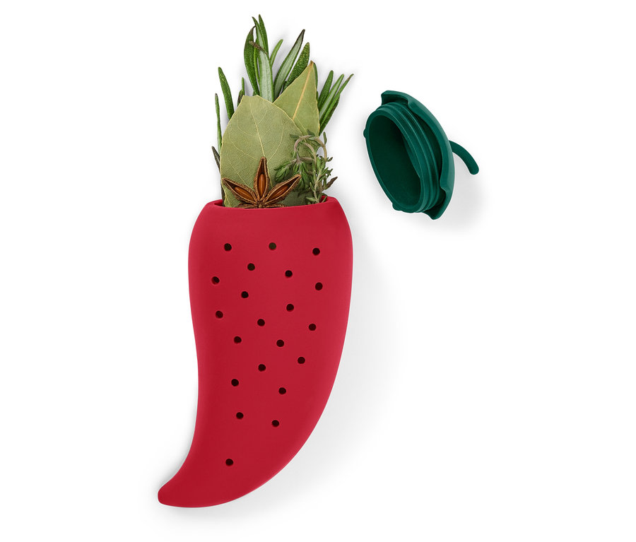 Červený silikonový louhovací sáček ve tvaru papriky naplněný bylinkami, s víkem vedle něj.