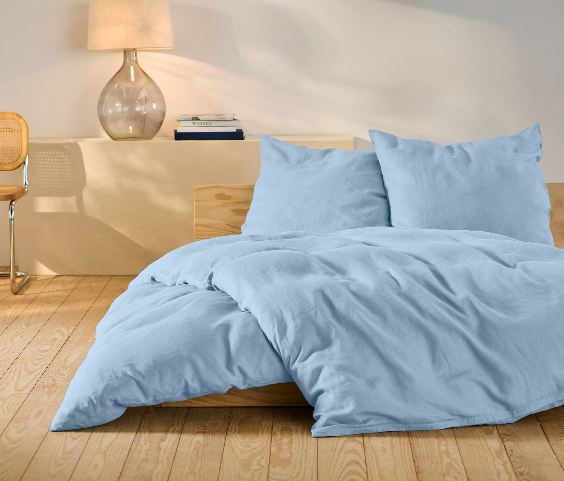Světle modré lněné povlečení standardní velikosti na posteli.