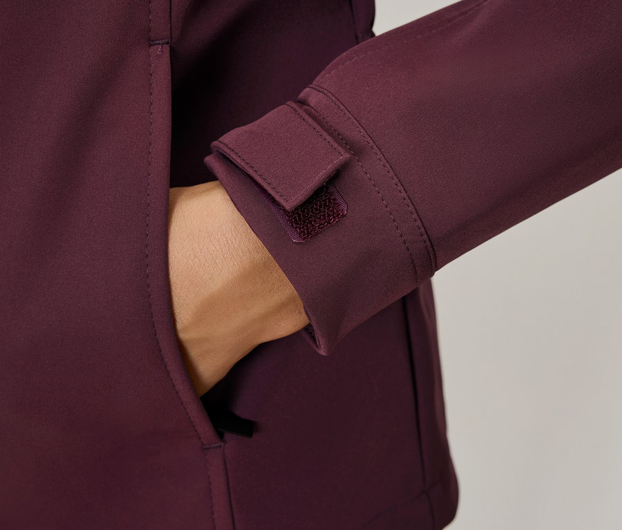 Ruka v kapse vínové bundy, detaily jako manžeta na suchý zip.