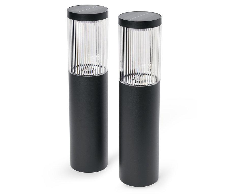 Dvě černé solární lampy stojí na bílém pozadí.