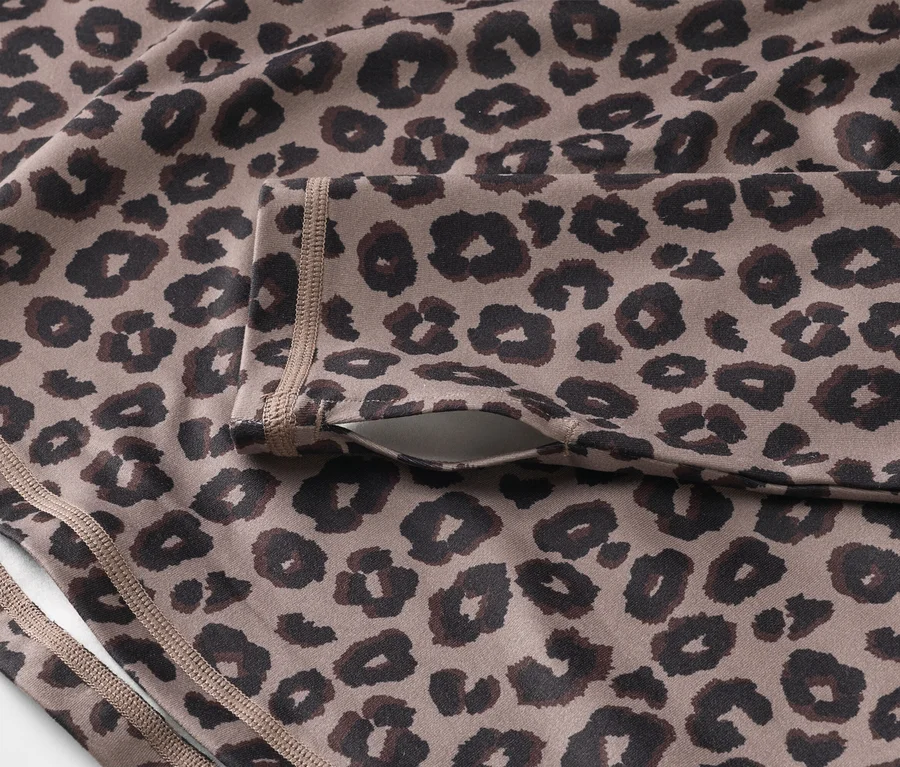 Detail sportovního topu s leopardím vzorem a kapsou na rukávu.