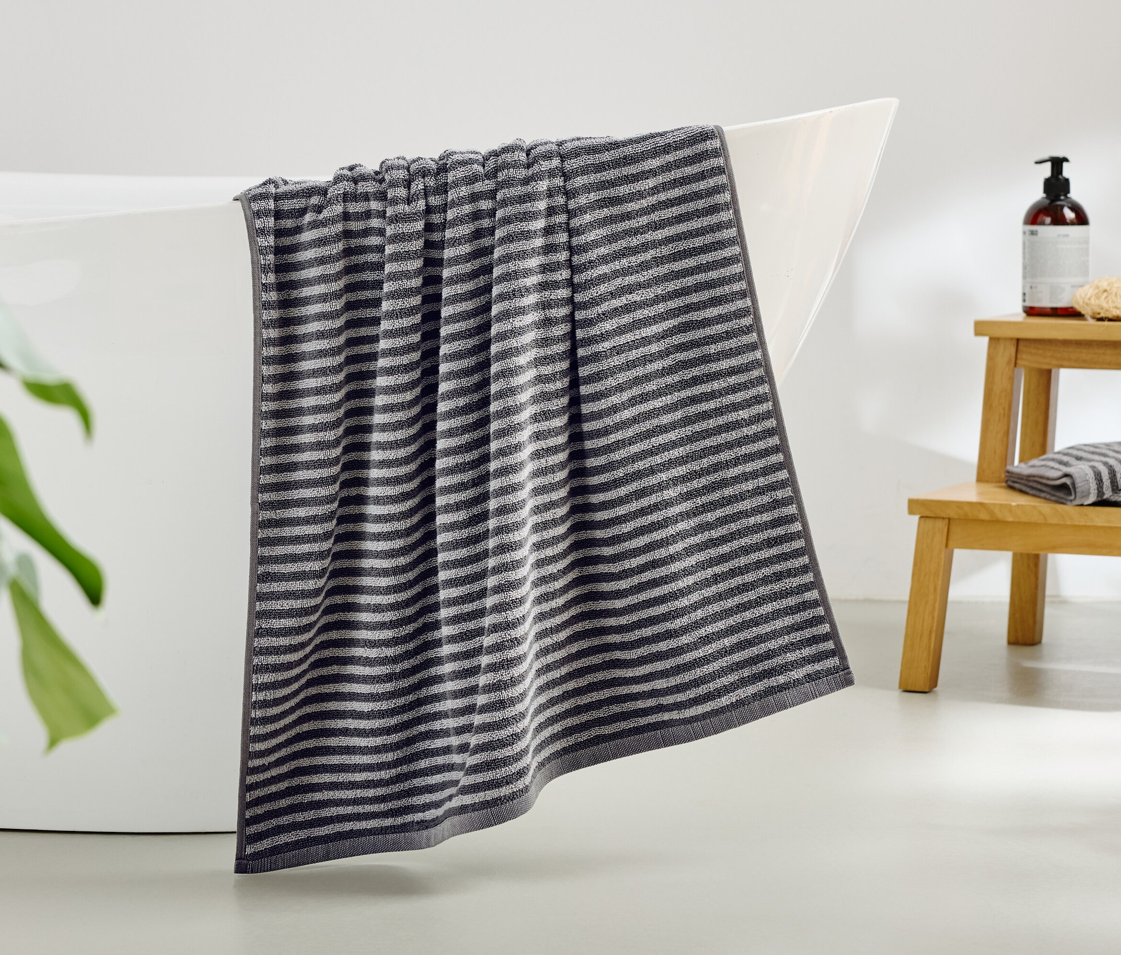 Pruhovaný ručník visí z okraje vany.