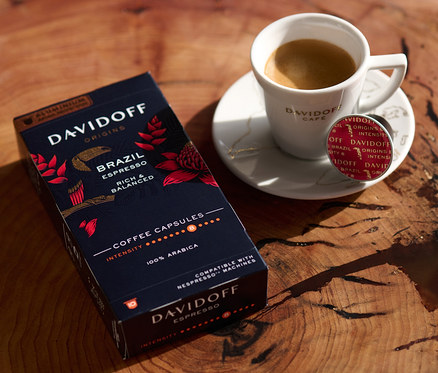 Na dřevěném stole stojí balení DAVIDOFF CAFÉ ORIGINS Brazil Espresso, šálek espressa a kapsle.