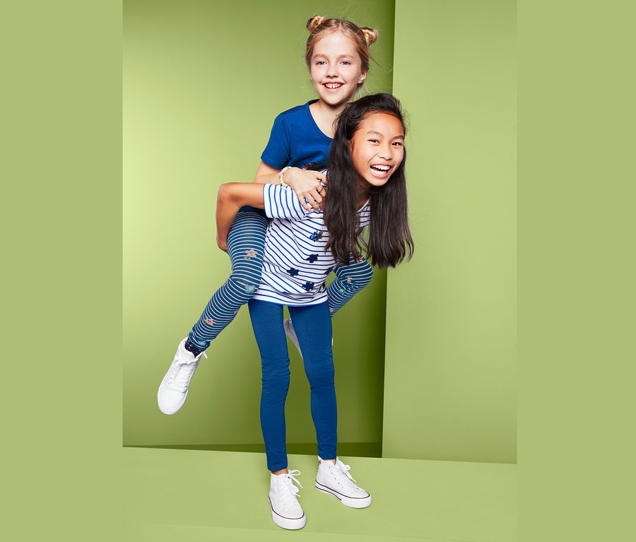 Dívka nese na zádech jinou dívku. Dívka na zádech má na sobě modré legíny, 2 ks.