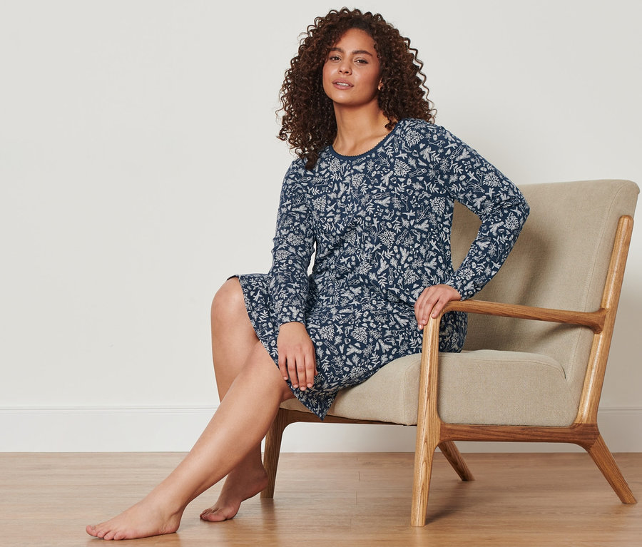 Žena sedí v křesle a má na sobě modrou noční košili.