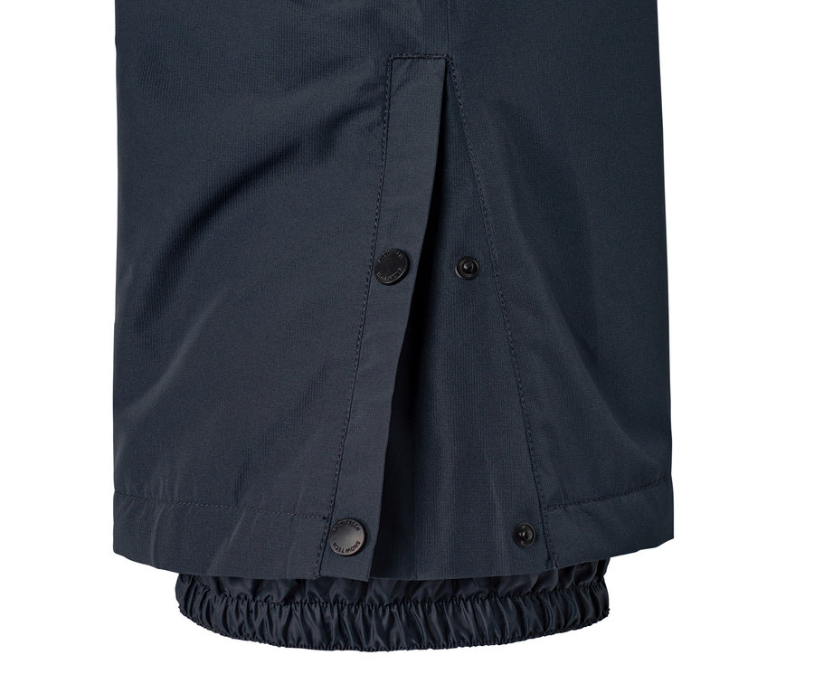 Detail modrých lyžařských kalhot s knoflíky a elastickým lemem.