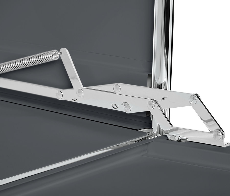 Detail šedé kovové odkládací skříňky CN3 s výklopnými dvířky a stříbrným mechanismem.
