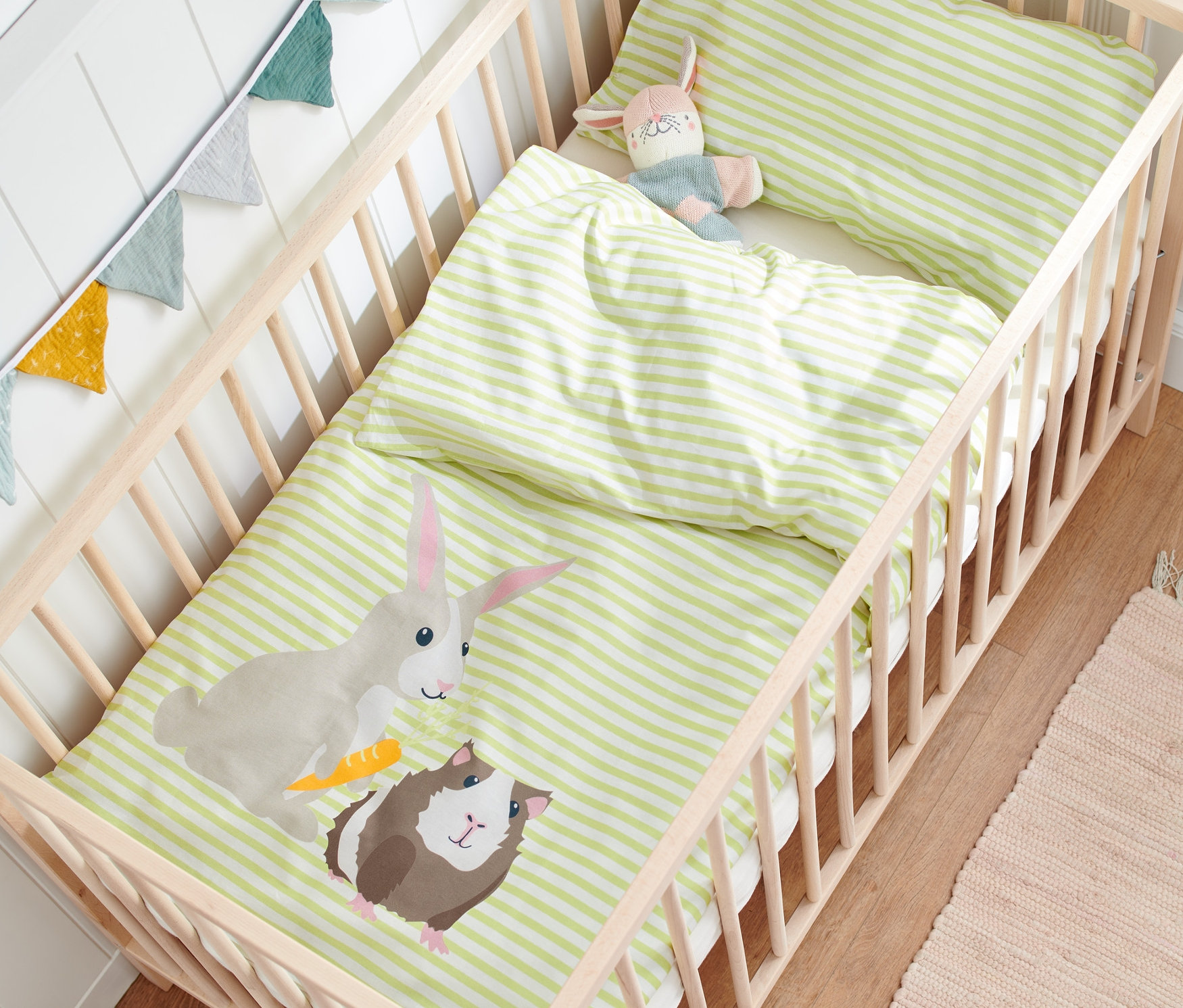 Dětské povlečení renforcé s motivem králíka a morčete v dřevěné postýlce.