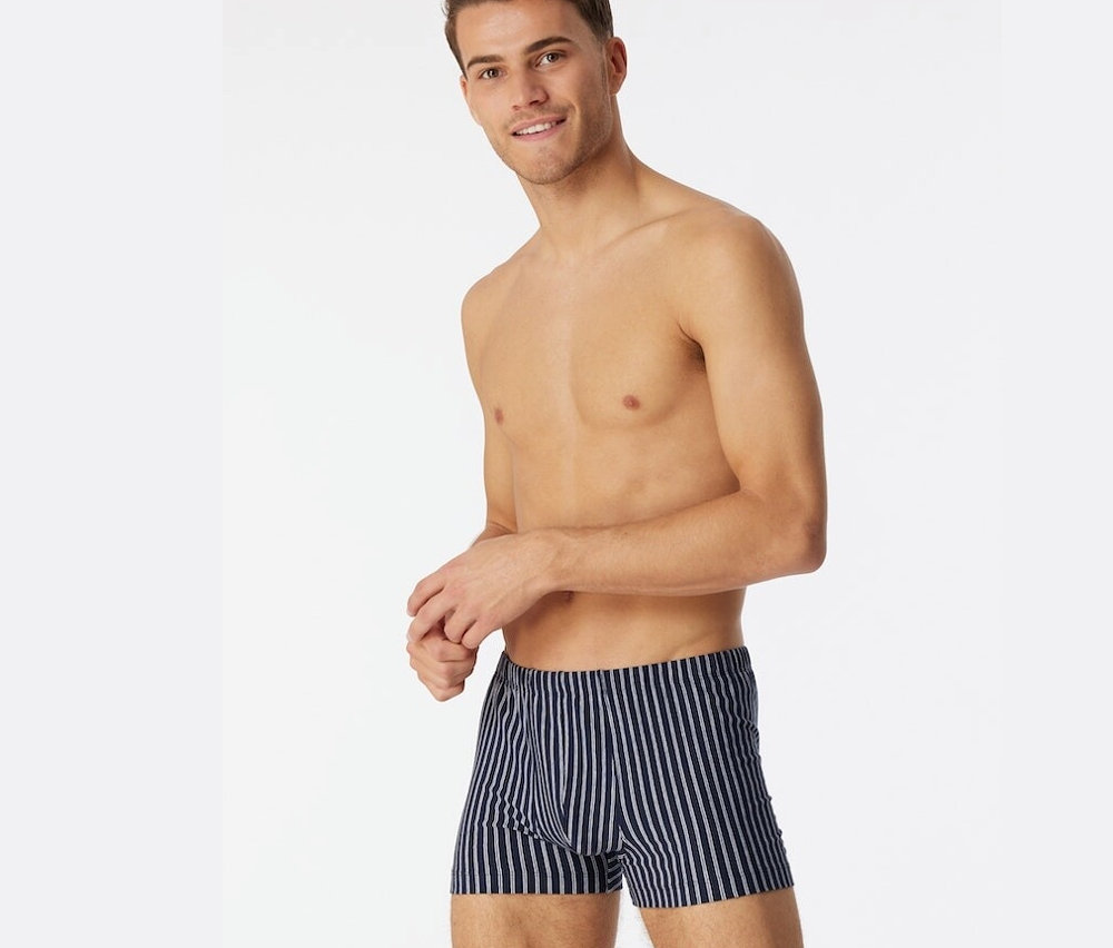 Muž s odhalenou horní polovinou těla má na sobě tmavě modré trenýrky SCHIESSER s biobavlnou.