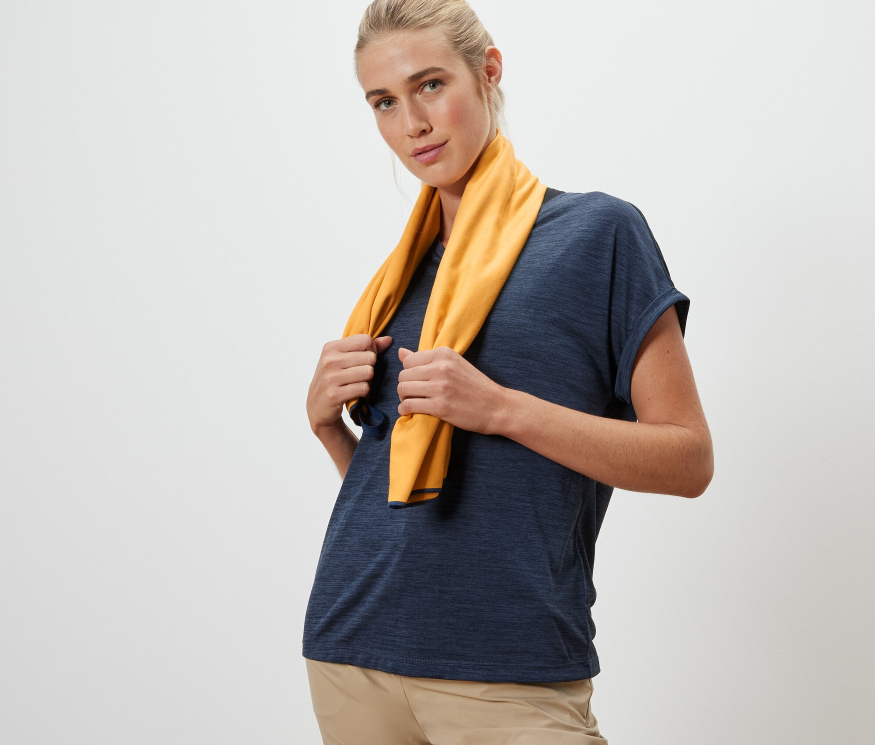 Žena drží na krku žlutý outdoorový ručník o rozměrech cca 50 x 100 cm.