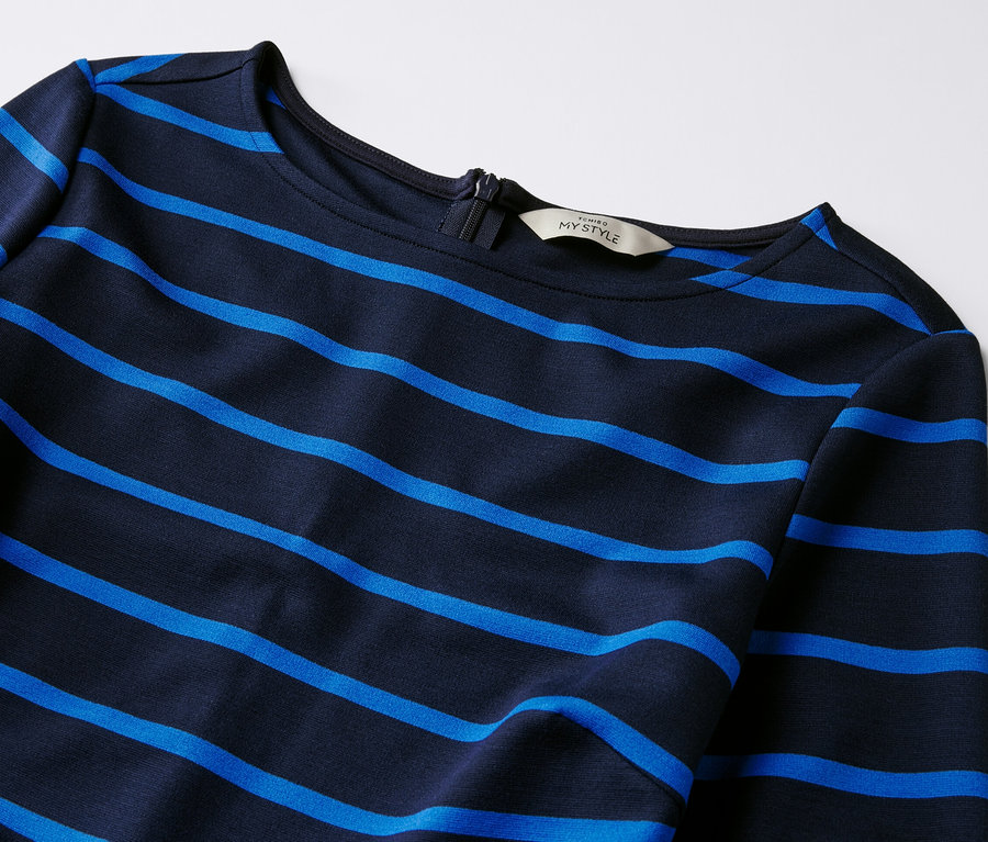 Detail žerzejových šatů s proužky.